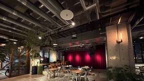 An indoor space with a stage, seating area, and a large window. - The HOTEL Well-hub Haneda (Kawasaki)
