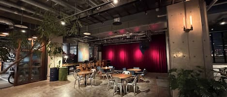An indoor space with a stage, seating area, and a large window.