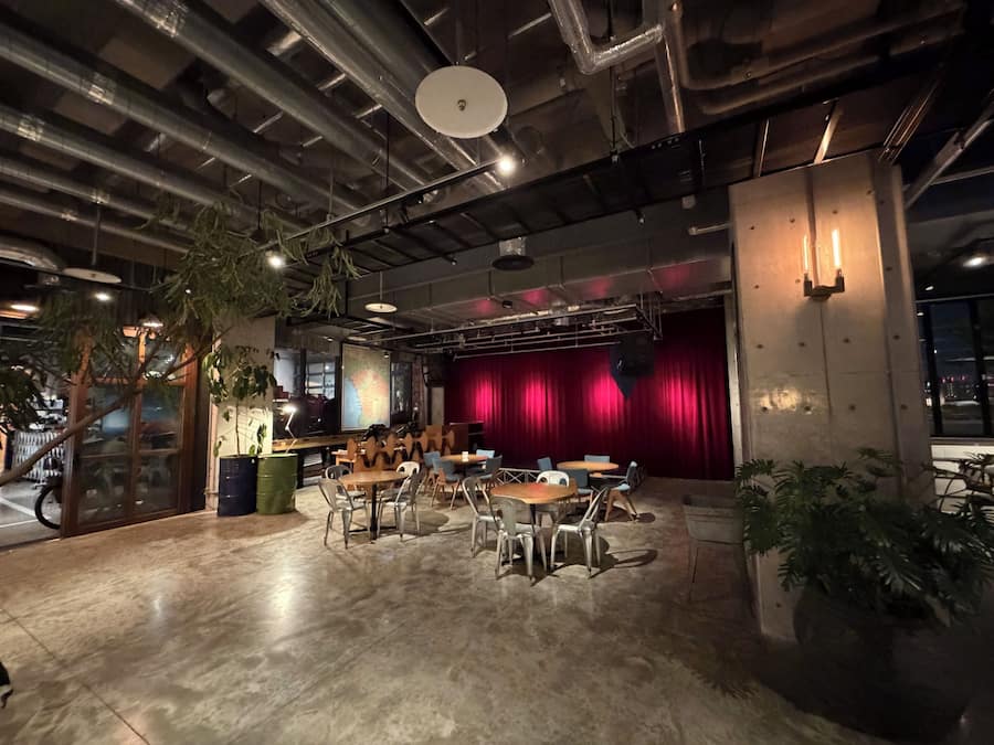 An indoor space with a stage, seating area, and a large window.