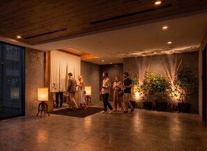 A modern hotel lobby with a wooden ceiling, a reception desk, and potted plants. - The HOTEL Well-hub Haneda (Kawasaki)