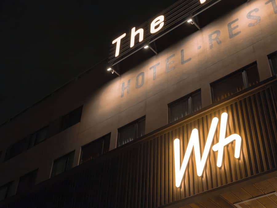 A hotel sign with 'The HOTEL RESTAURANT' and a prominent illuminated 'WH' sign.