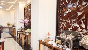 A buffet setup with various food items and a decorative wall. - Bazan Xanh Hotel (Buon Ma Thuot)
