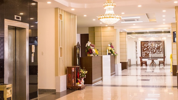 A hotel lobby with a reception desk, a chandelier, a reception area, and a dining area with chairs. - Bazan Xanh Hotel (Buon Ma Thuot)