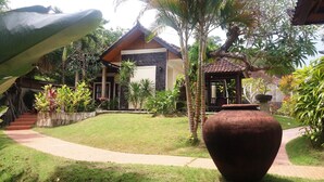 A traditional house with a stone wall, a tiled roof, and a garden with a large pot and various plants. - Vantage Point Villas (Ungasan)