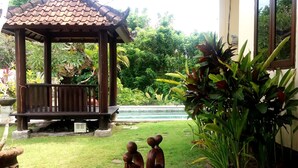 A gazebo with a tiled roof and a bench, surrounded by lush greenery and a swimming pool. - Vantage Point Villas (Ungasan)