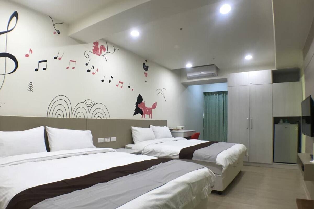 A hotel room with two beds, a desk, a TV, and a wardrobe.
