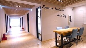 A hallway with a wooden ceiling, a conference table with chairs, and a wall with 'Formosa Boulevard Music City' signage. - Formosa Boulevard Music City (Kaohsiung)