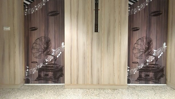 A hallway with two mirrored doors featuring a central vertical panel and a decorative design with musical notes and a gramophone. - Formosa Boulevard Music City (Kaohsiung)
