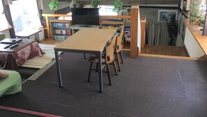 A room with a dining table, chairs, a television, bookshelves, and potted plants. - Kitashiga Lime Light (Yamanouchi)