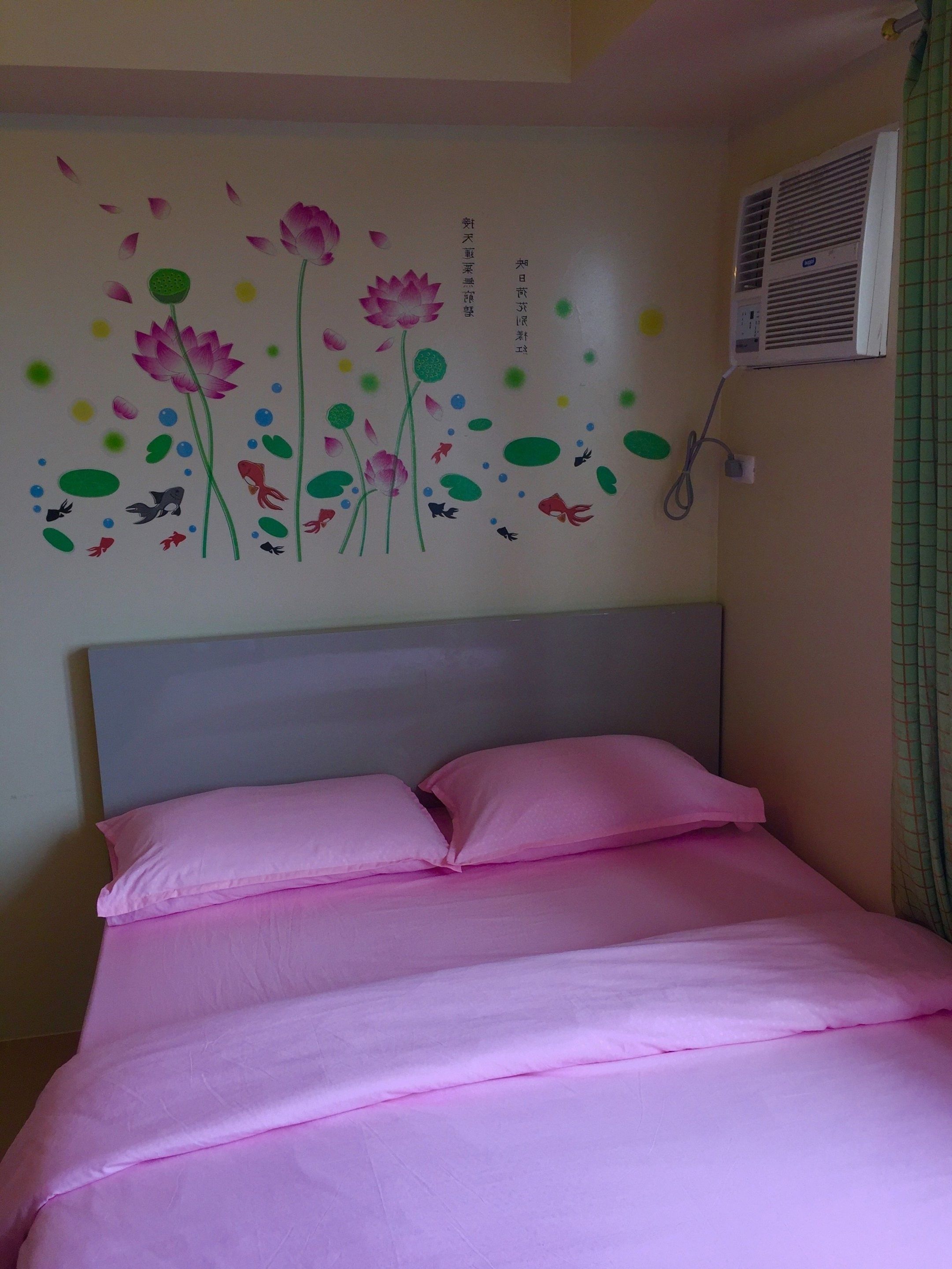 Une chambre avec un lit, une décoration florale sur un mur et un appareil de climatisation.
