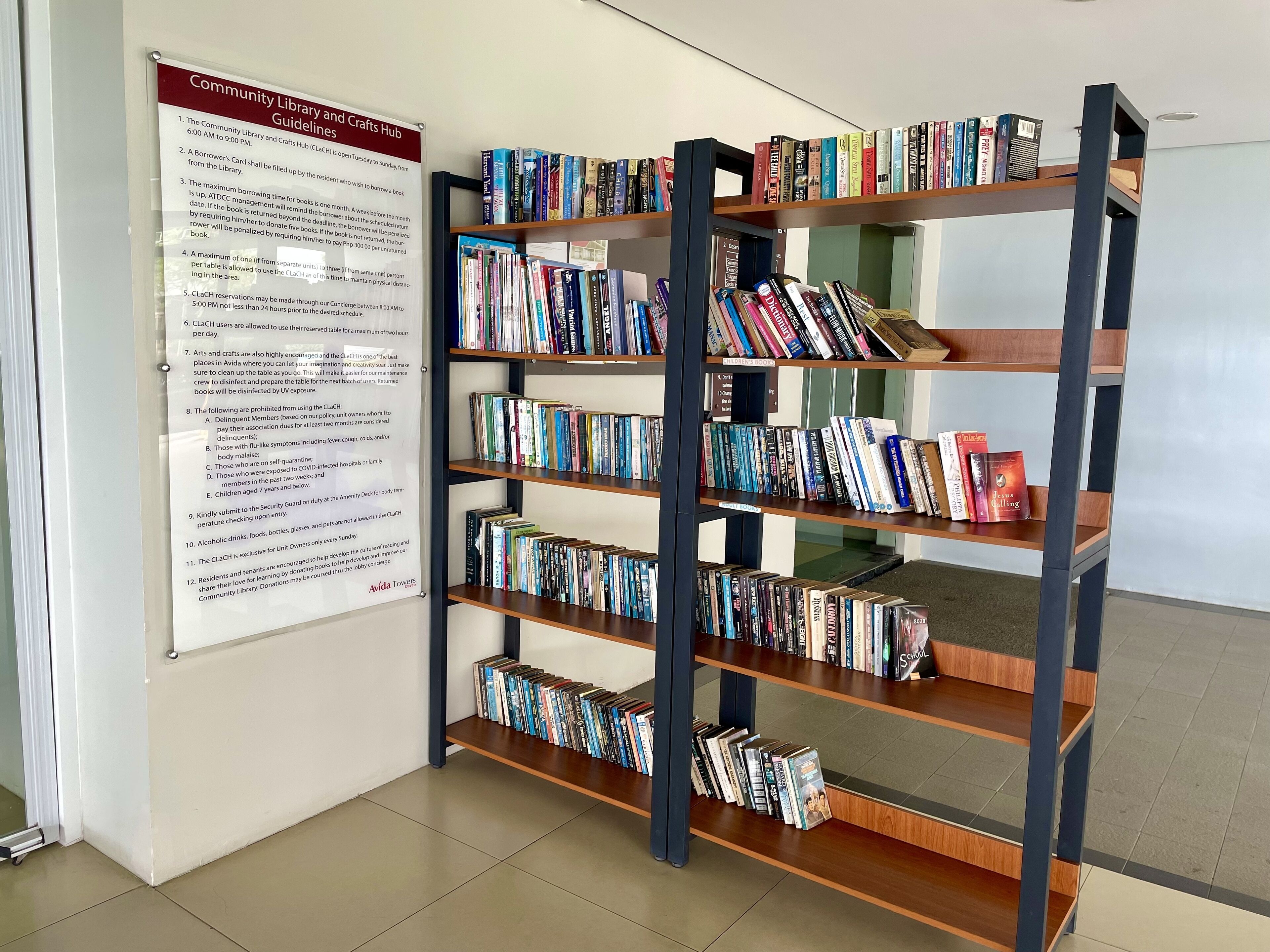 Uma biblioteca com estantes de livros e um aviso com as normas da biblioteca comunitária.
