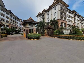 A multi-story residential building with balconies, a gated entrance, and a small pavilion. - 1BR Unit For Rent One Oasis Condominium (Davao)