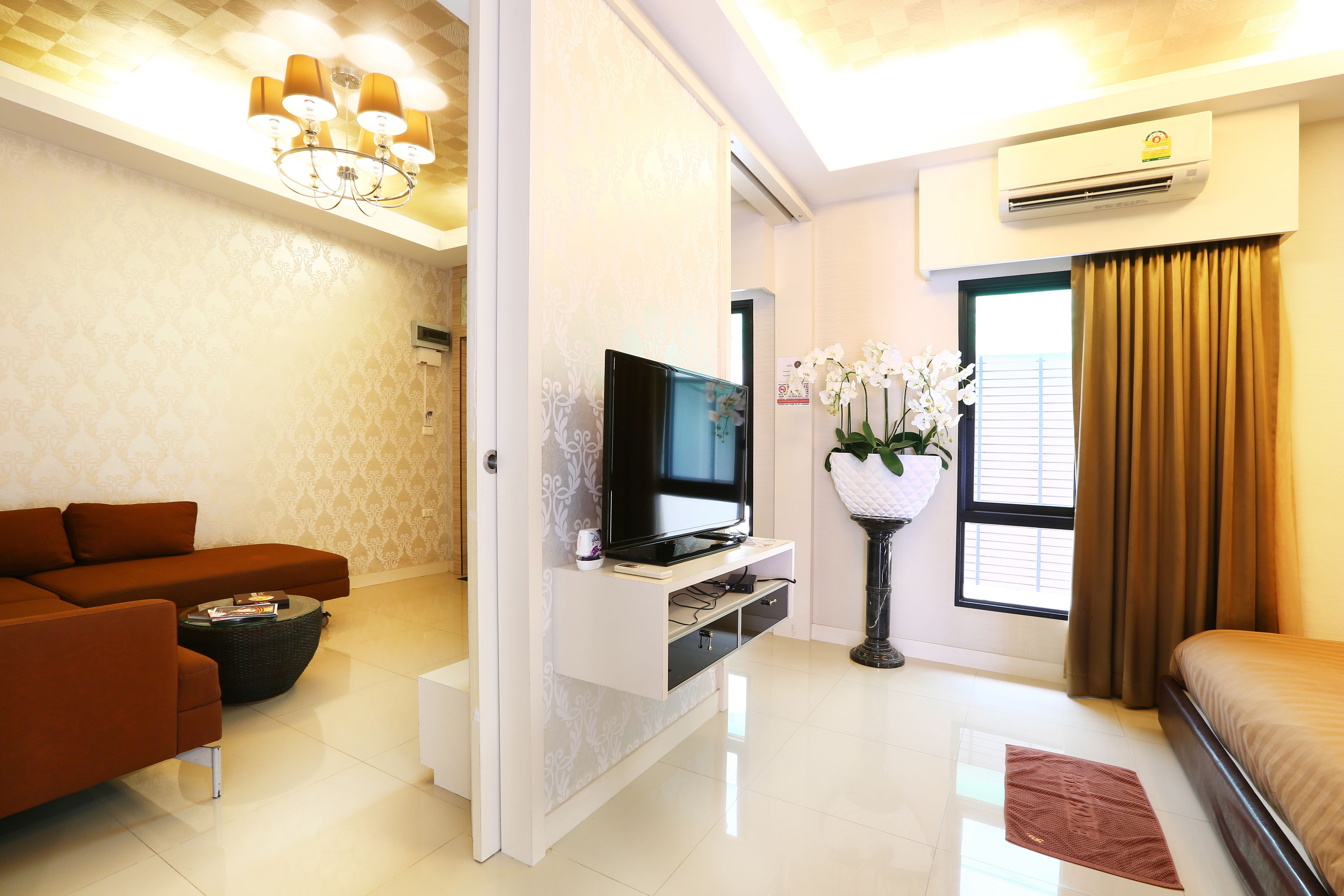 A modern living room with a sofa, TV, and a decorative plant.