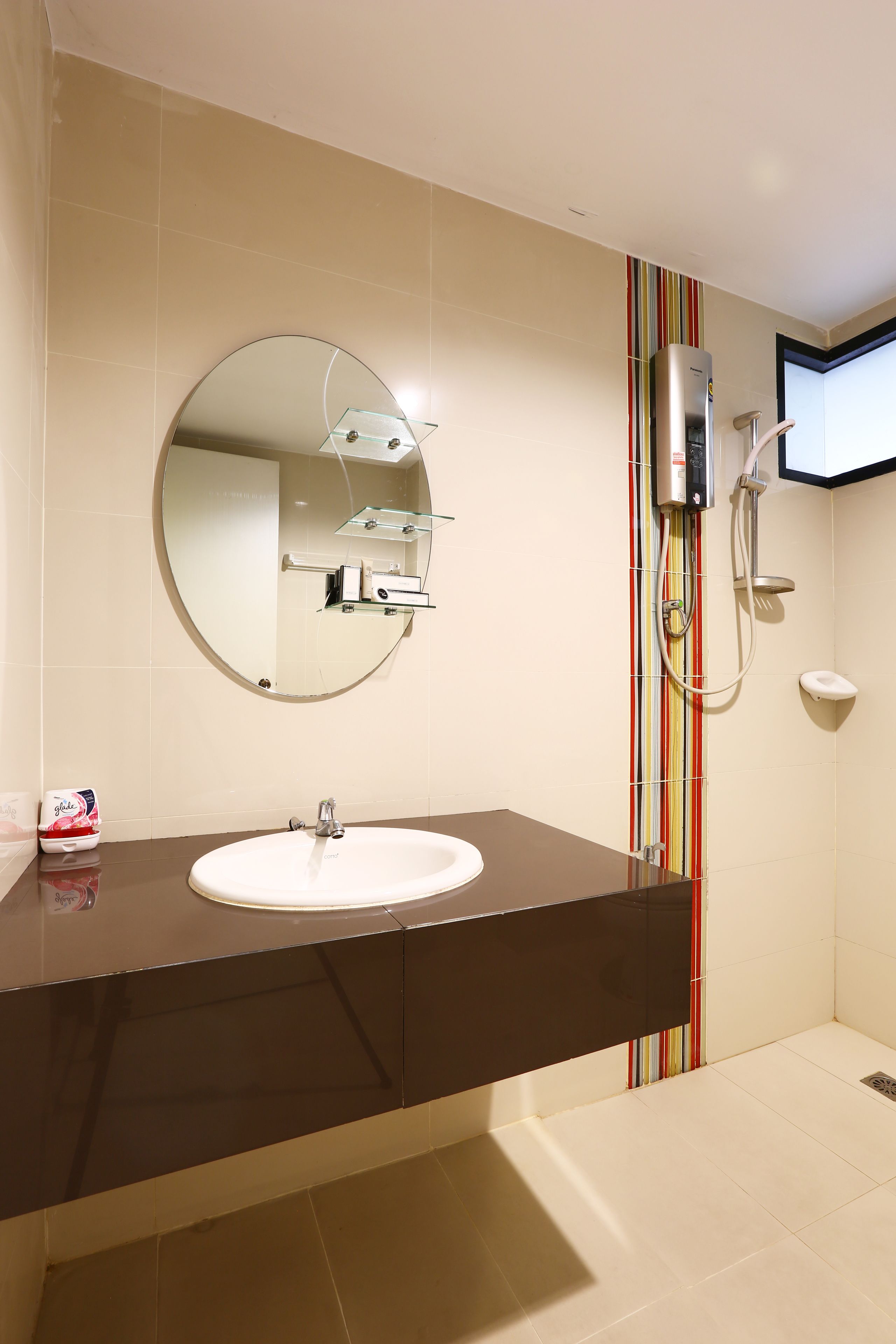 Een moderne badkamer met een ronde spiegel, een witte wastafel en een douche met een handdouche.