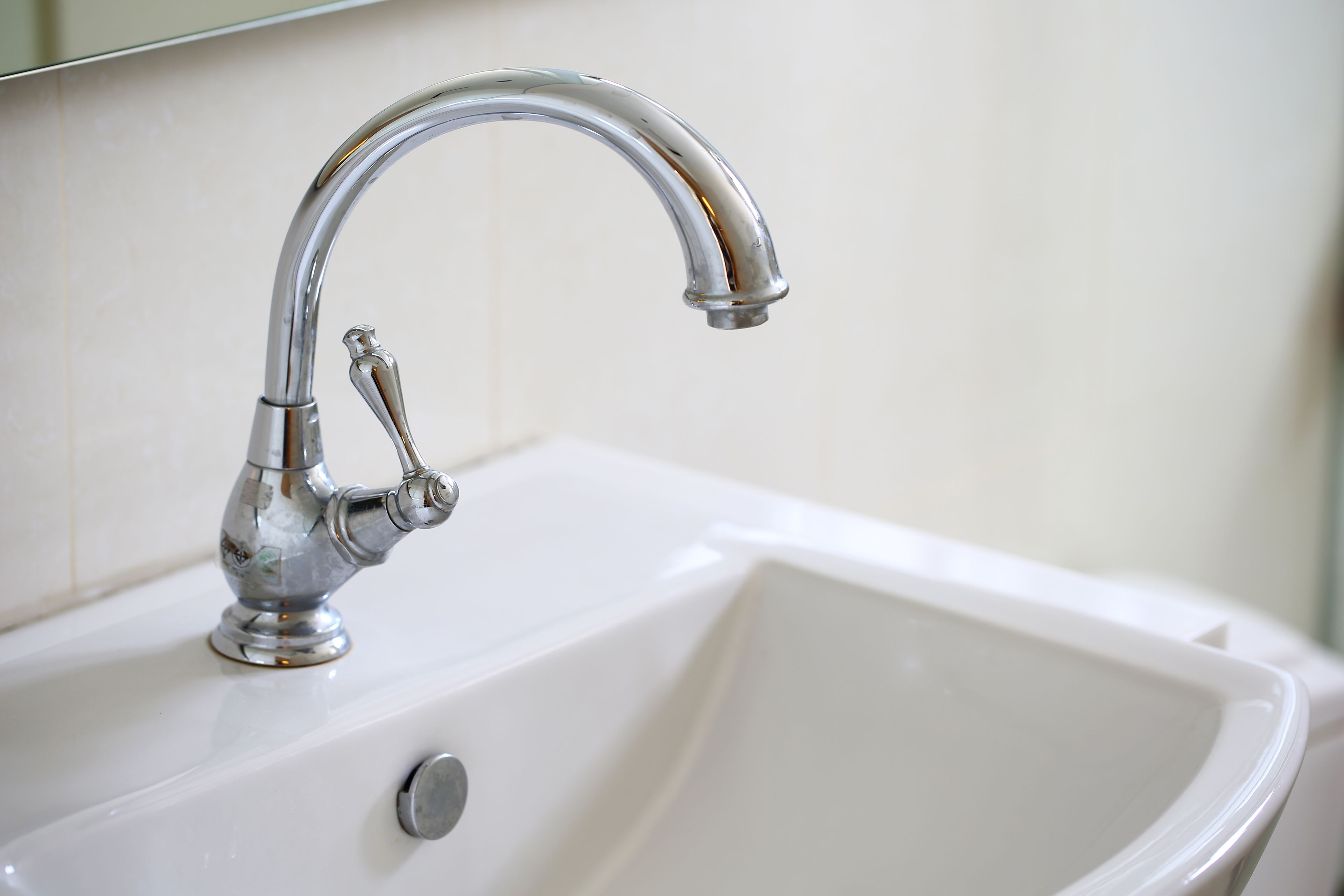 A white bathroom sink with a chrome faucet and a single round drain.
