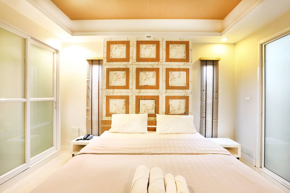 A hotel room with a large bed, a bedside table with a phone, and a wall with framed pictures.