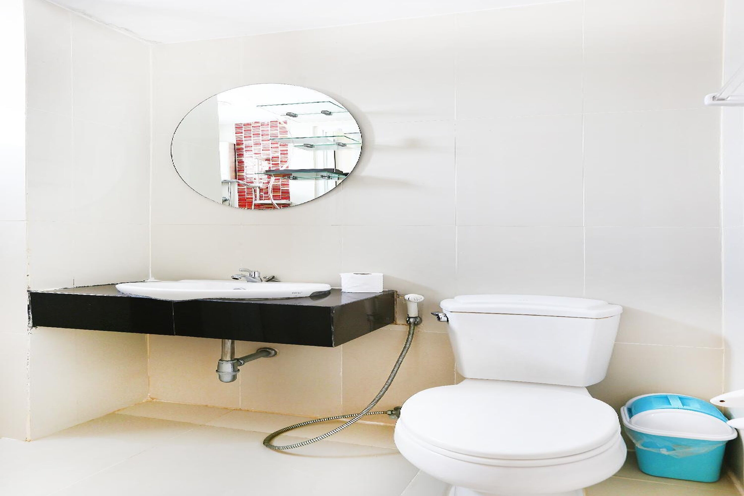 A bathroom with a white sink, black countertop, and a round mirror above it.