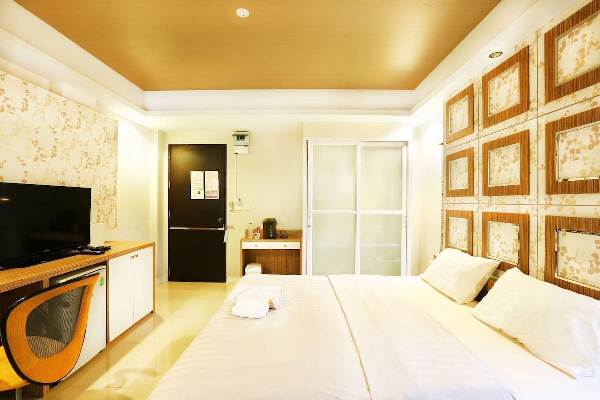A hotel room with a bed, a TV, a desk, and a wardrobe.