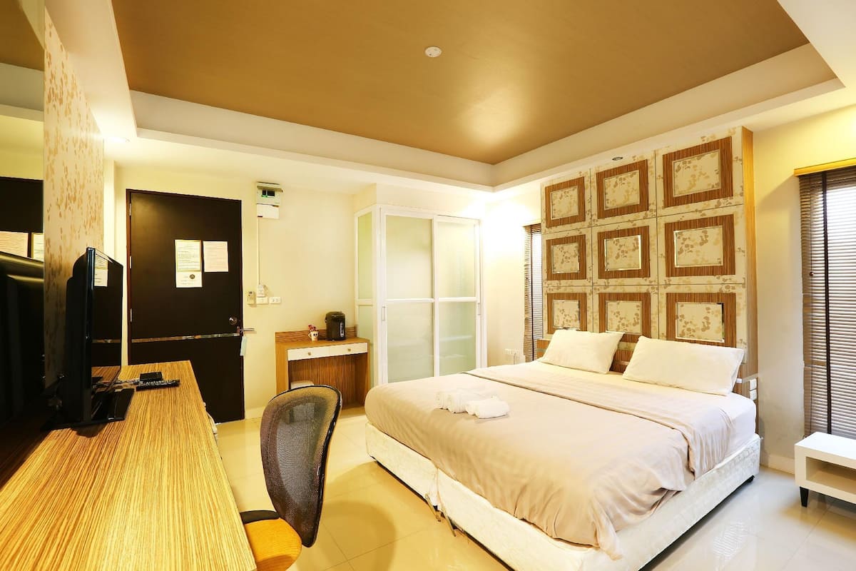 A hotel room with a bed, desk, chair, and a television.