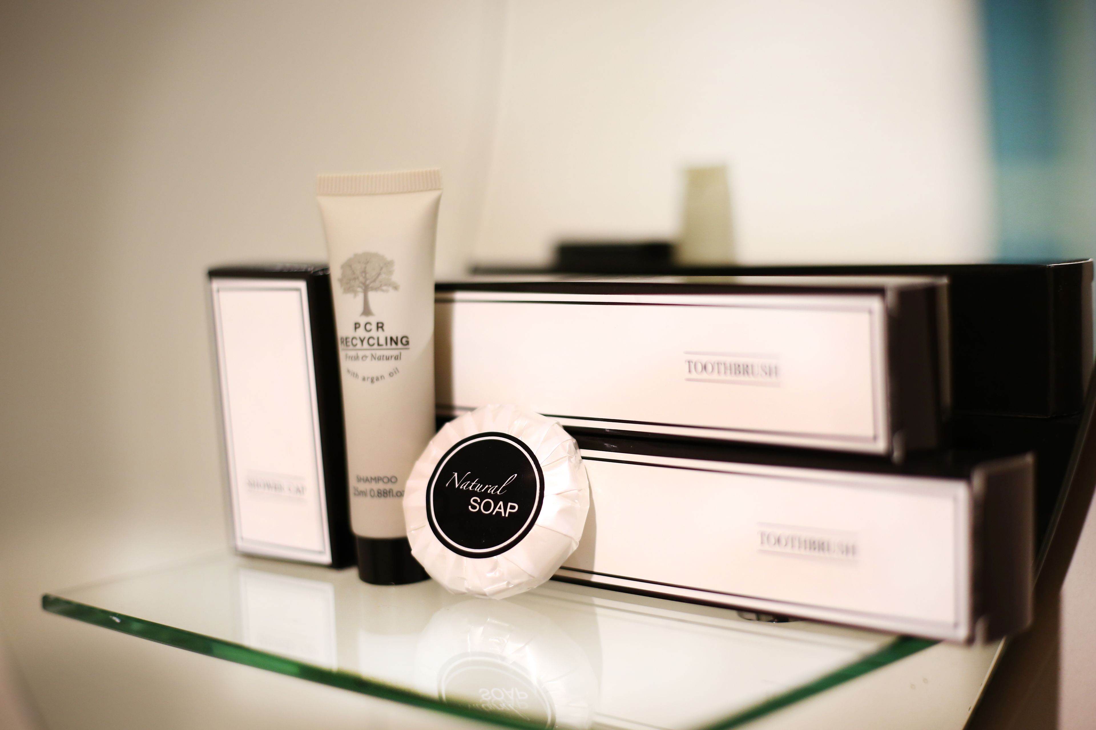 A display of toiletries including a tube of cream, a bar of soap, and a toothbrush set on a glass shelf.
