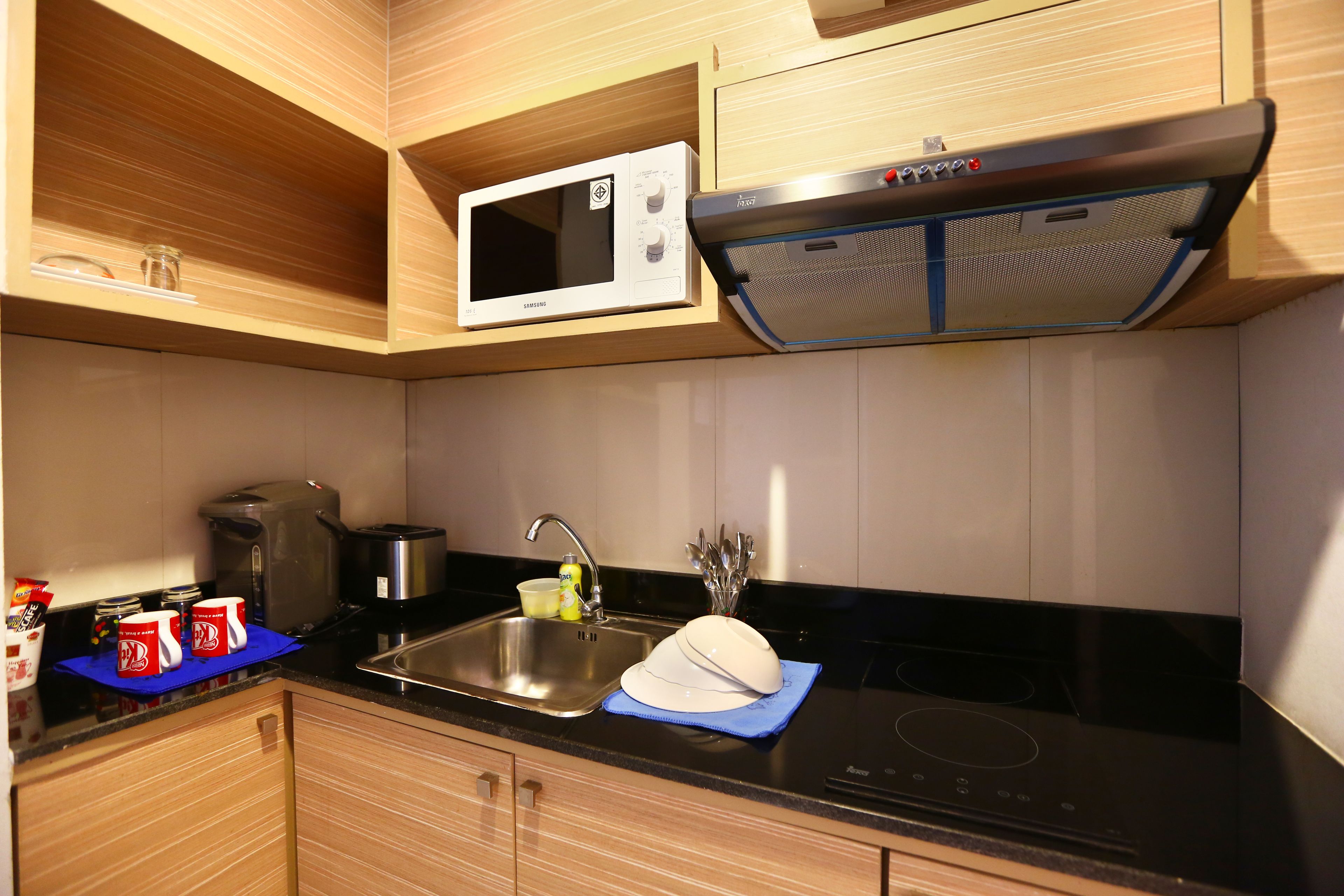 Eine moderne Küche mit Mikrowelle, Herd, Spüle und Holzschränken.