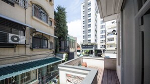 A narrow urban alleyway with buildings on either side, featuring balconies and a small courtyard with a wooden deck. - Tainan Travel Inn (Tainan)