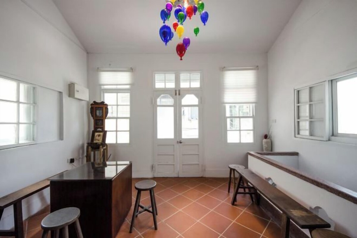 A room with a wooden bar, two stools, a bench, and a colorful balloon decoration.