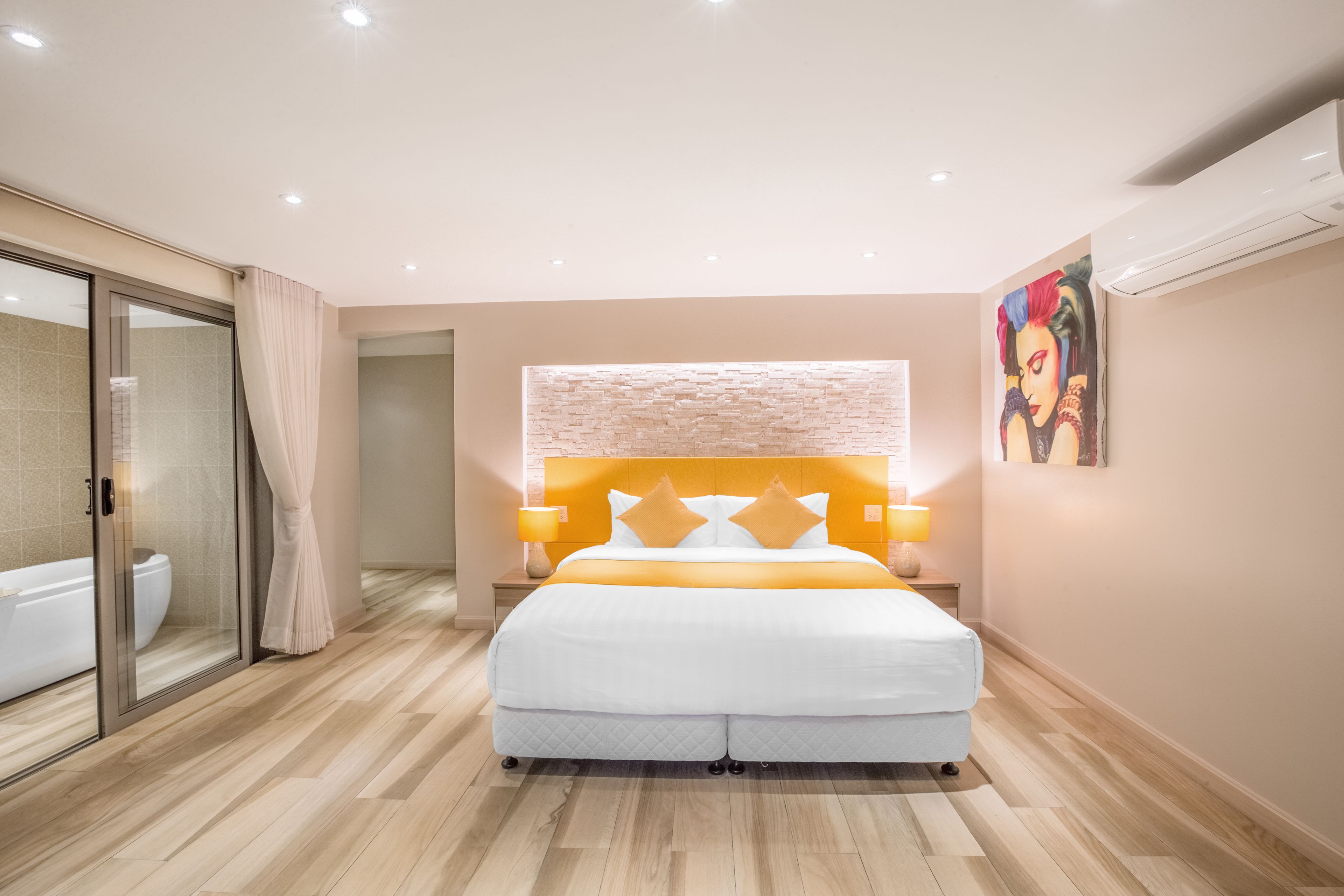 A modern bedroom with a large bed, a glass shower enclosure, and a painting on the wall.