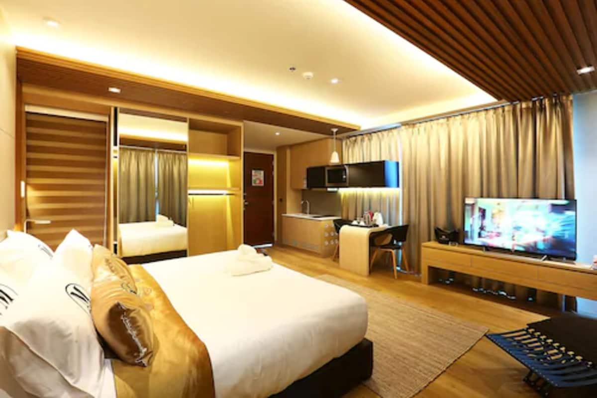 Habitación de hotel con una cama grande, un escritorio, un televisor y un armario.