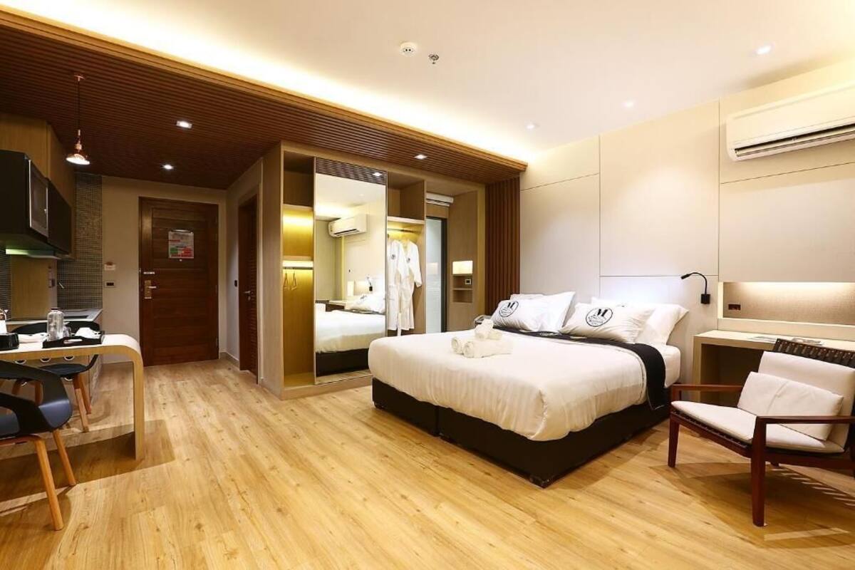 Una habitación de hotel con una cama, un escritorio con una silla, un armario y un espejo.