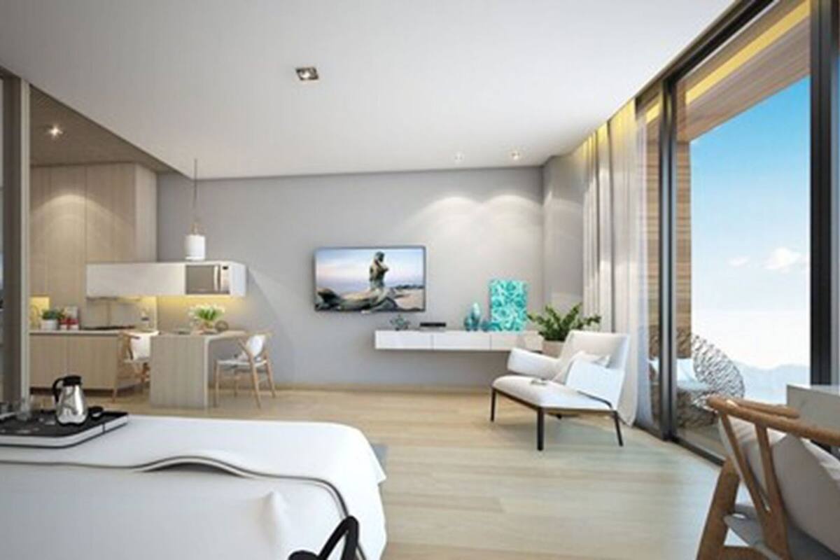 Habitación de hotel moderna con una cama grande, un escritorio, una silla, un televisor y vistas al exterior.