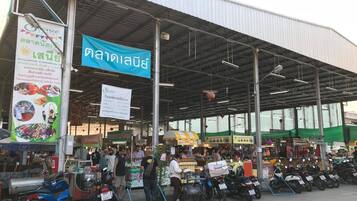 Zona de mercado techada con varios puestos y motocicletas estacionadas al frente.