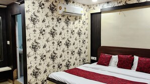 A bedroom with a bed, a ceiling fan, an air conditioner, and a patterned wall. - Hotel Satpura Safari (Pipariya)