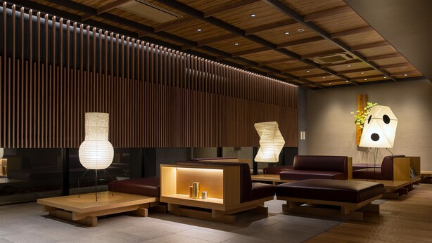 A modern lobby with wooden paneling, seating areas, and decorative lamps.