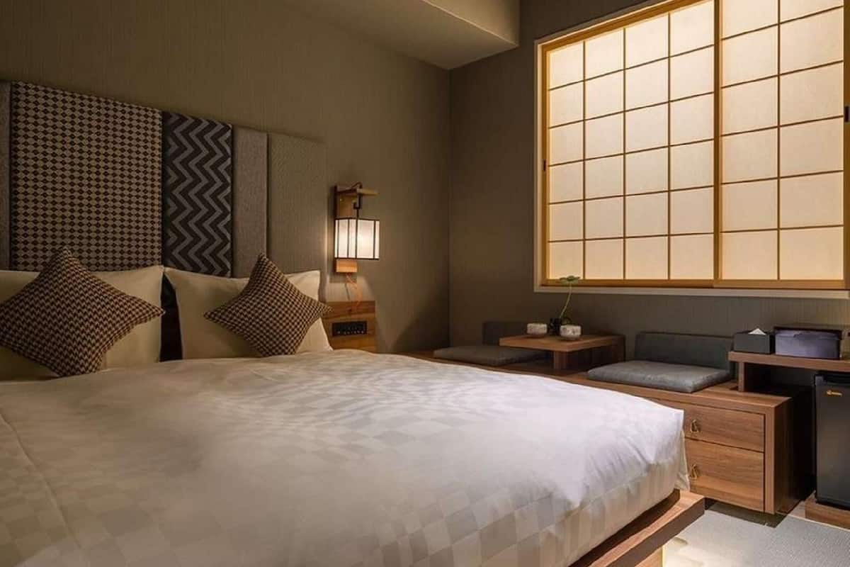 A hotel room with a large bed, bedside tables, a nightstand, a desk, and a window with a view.