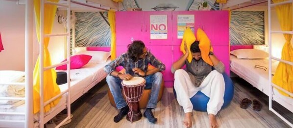 A dormitory room with bunk beds, a drum, and a poster on the wall. - goSTOPS Udaipur (Udaipur)