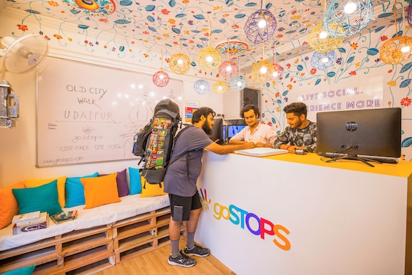 A cozy workspace with a whiteboard, a sofa with colorful cushions, and a desk with a computer. - goSTOPS Udaipur (Udaipur)