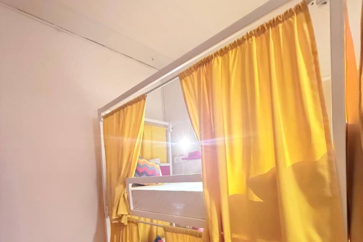 Una cama litera con cortinas amarillas y un espejo.