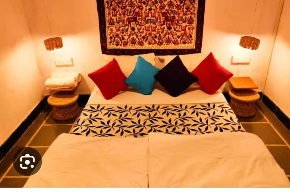 Habitación de hotel con cama, almohadas, un tapiz en la pared y dos mesitas de noche.