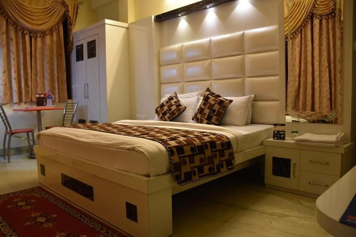 A bedroom with a large bed, a bedside table, a wardrobe, and a desk with a chair.
