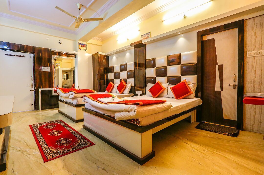A hotel room with a large bed, a ceiling fan, and a red carpet.