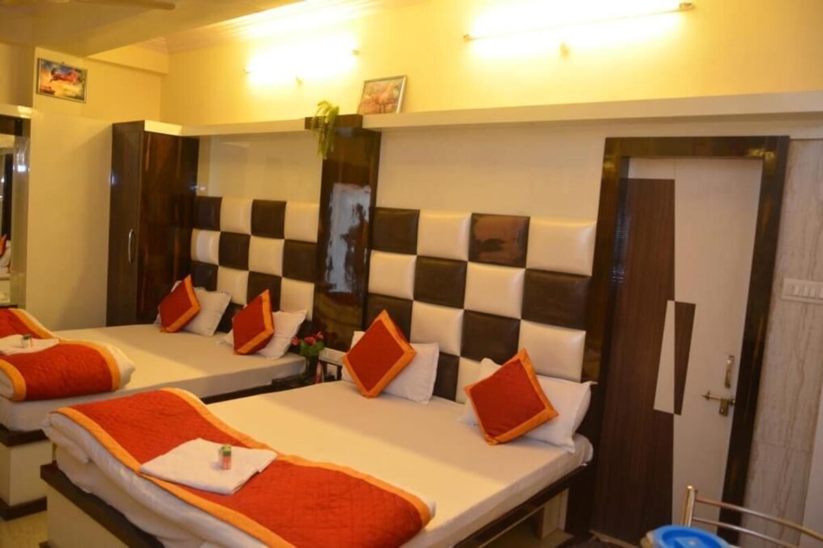 A hotel room with two beds, each with a red and white bedspread, and a checkered headboard.