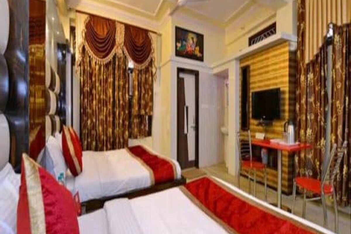 A hotel room with two beds, a TV, a desk, and a mirror.