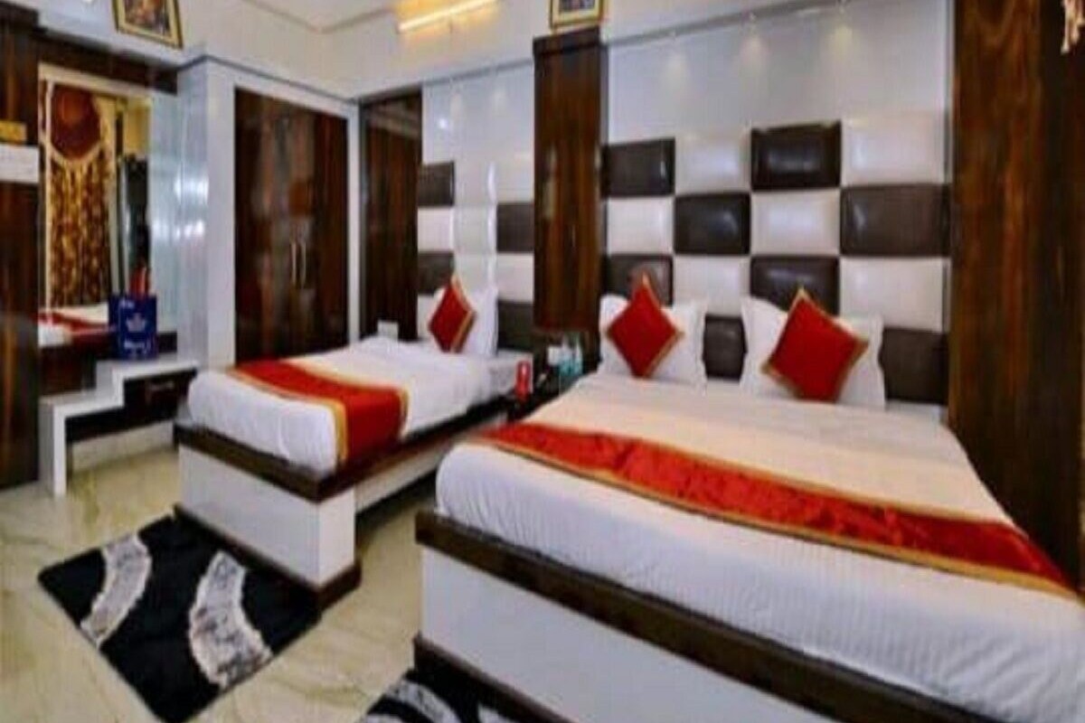 A hotel room with two beds, a large mirror, and a modern design with wooden headboards and red accents.