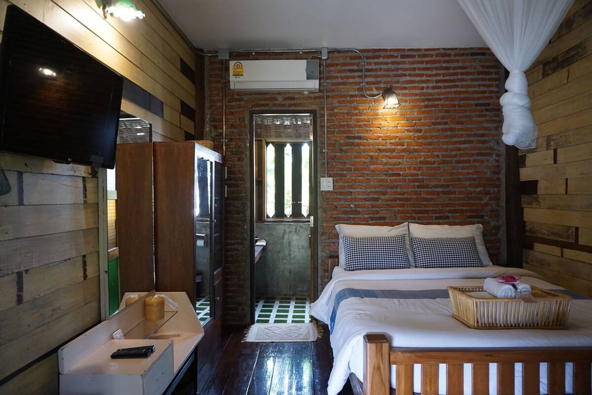 Una habitación con cama, televisión, armario y espejo.