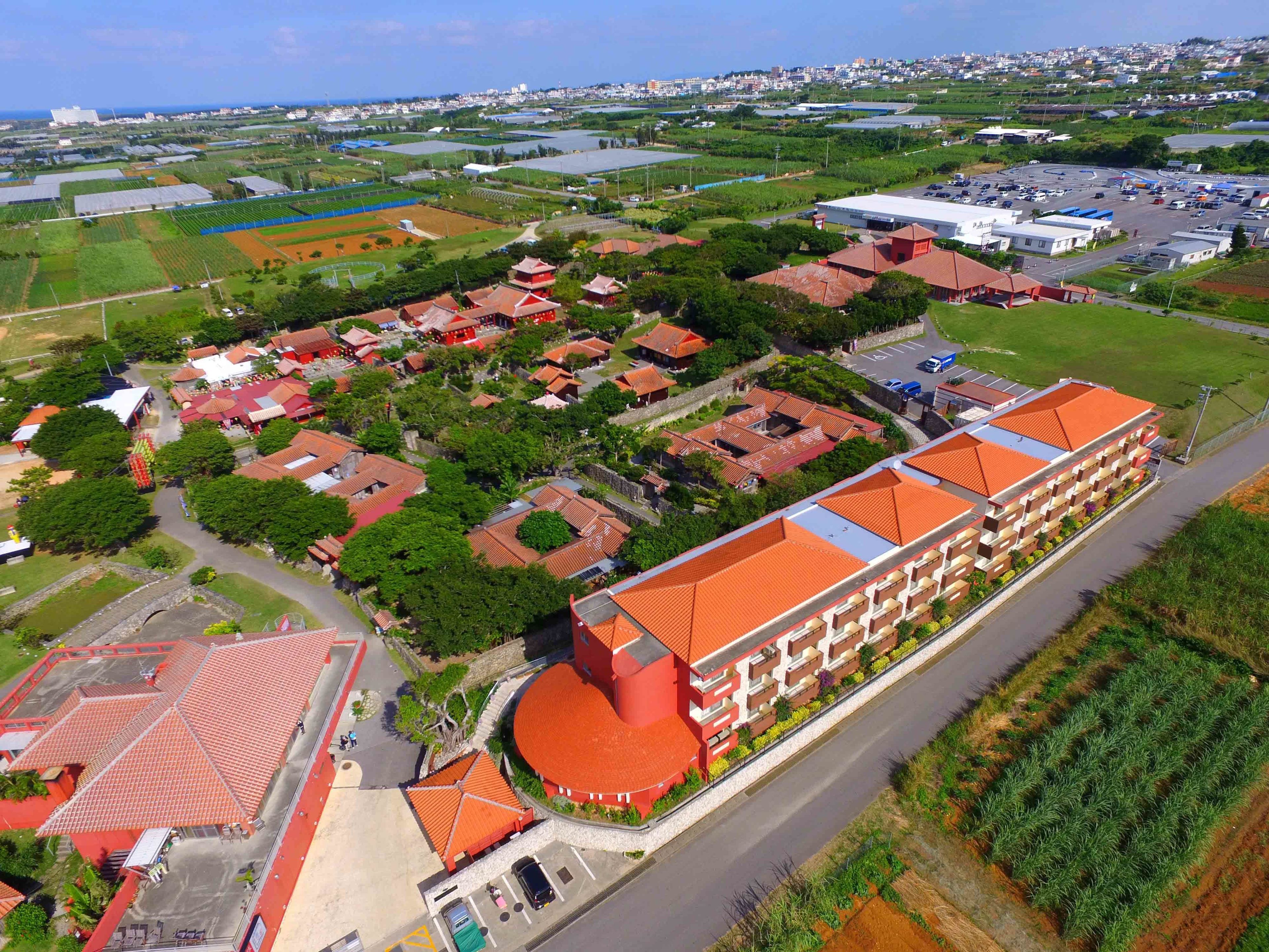 A large building with a red roof, surrounded by smaller red-roofed structures, likely part of a resort or hotel complex.
