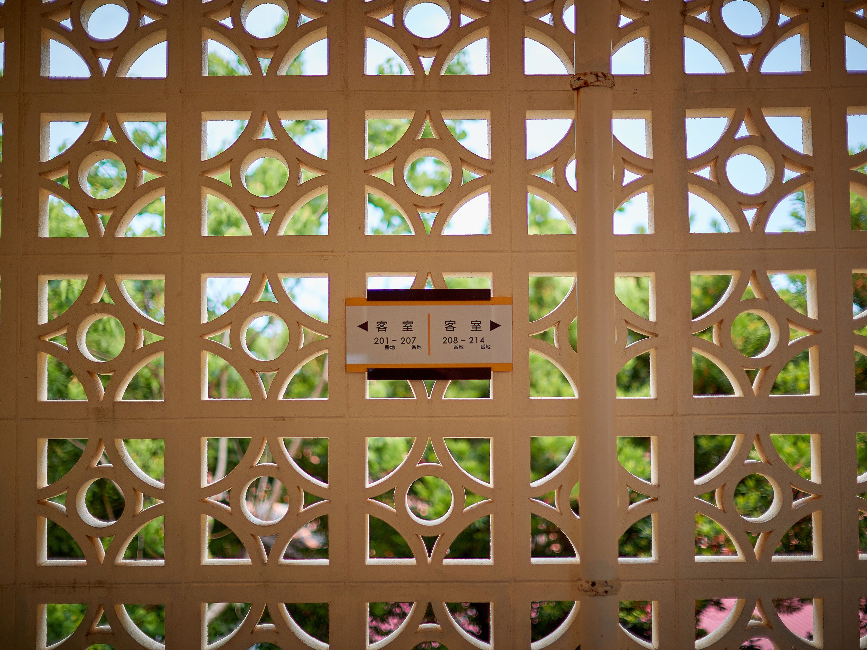 A decorative wooden partition with a sign indicating room numbers 201-207 and 208-214 for the guest room.