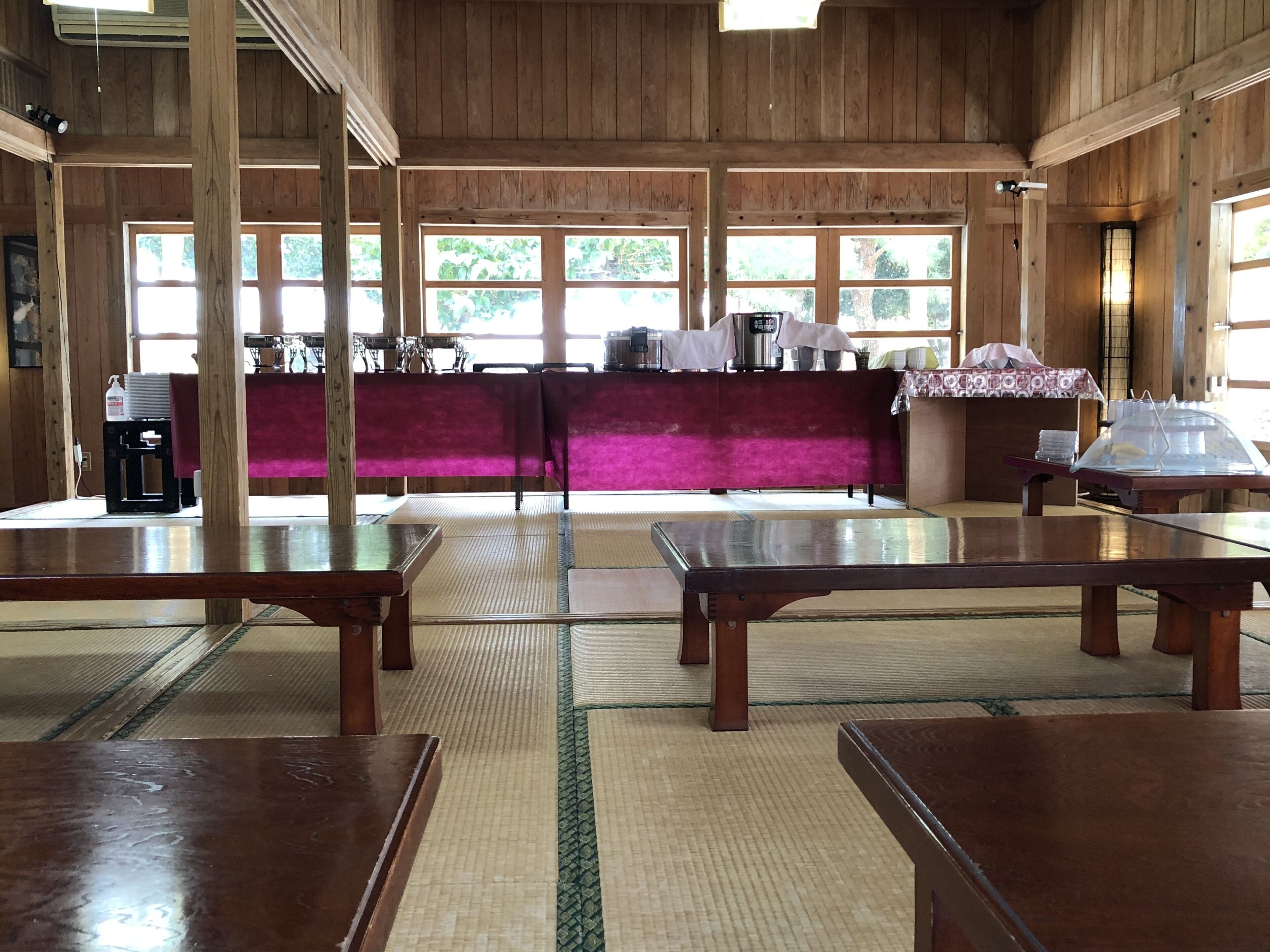 Une pièce de style japonais traditionnel, avec des tatamis, des tables en bois et un espace d’accueil doté d’un comptoir violet.