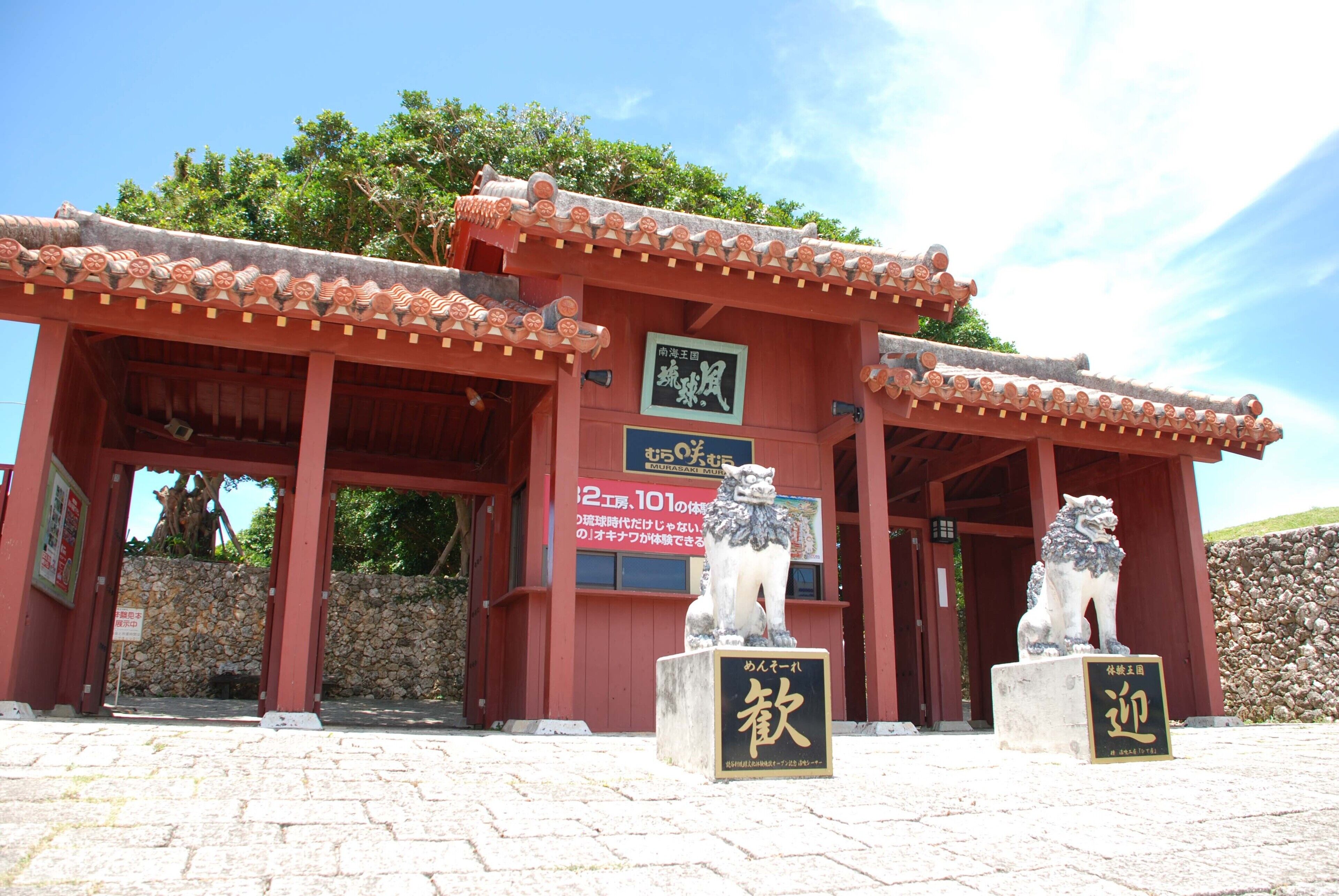 A traditional Japanese building with a tiled roof and stone walls. There are two stone lion statues in front.