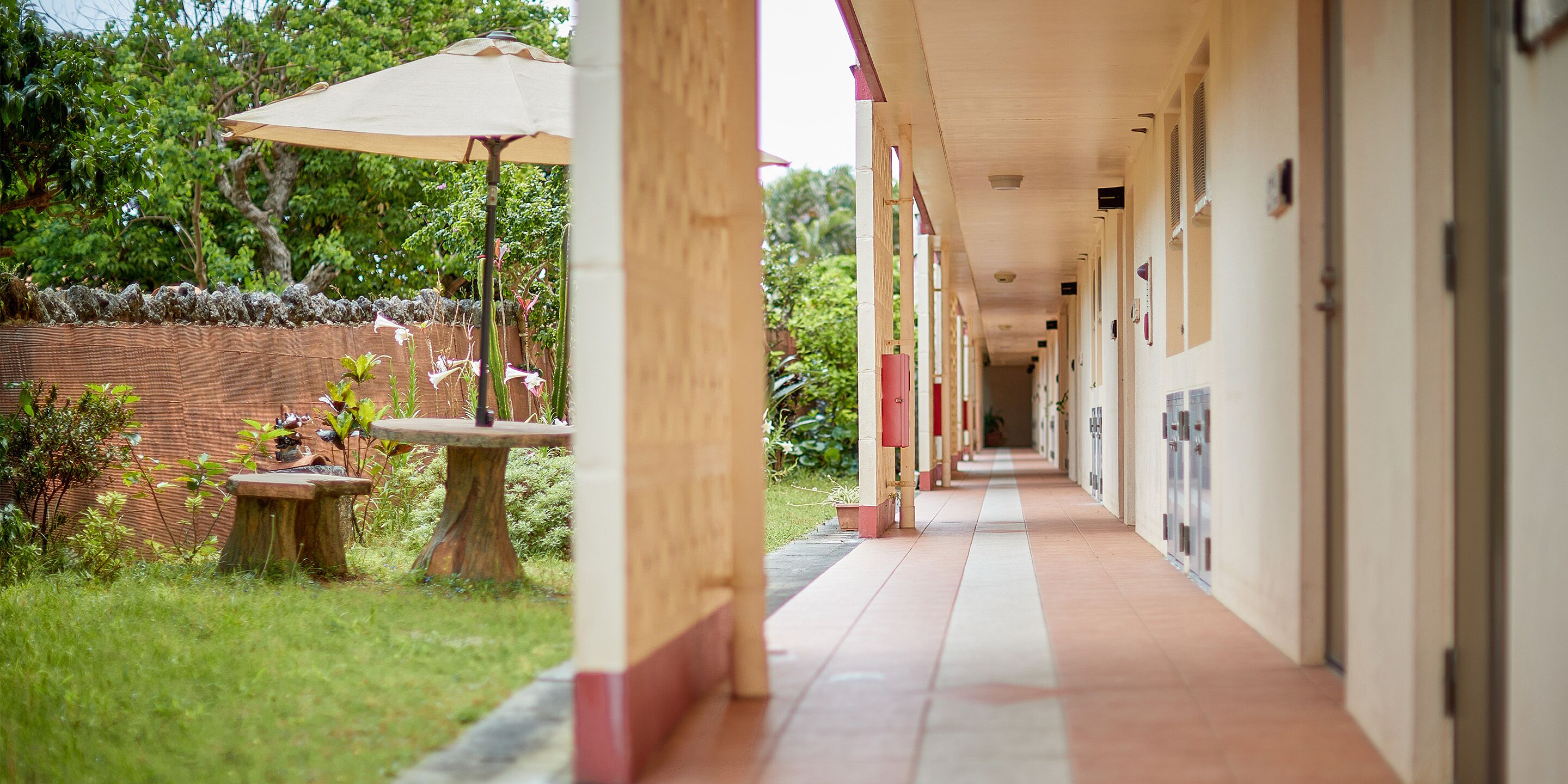 A covered corridor with a tiled floor, leading to a series of rooms.